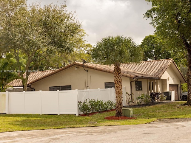 view of property exterior with central AC and a lawn