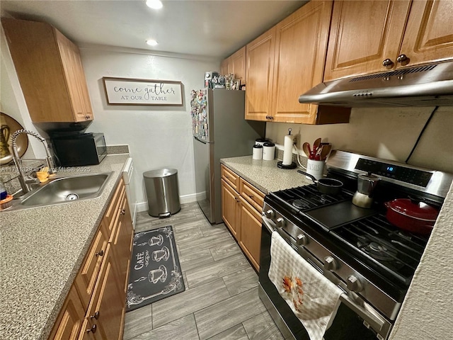 kitchen featuring stainless steel appliances, light stone countertops, and sink