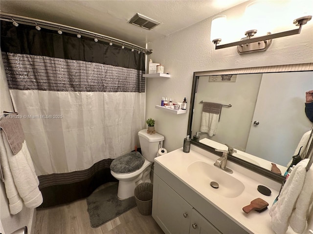 bathroom featuring vanity, wood-type flooring, toilet, and a textured ceiling