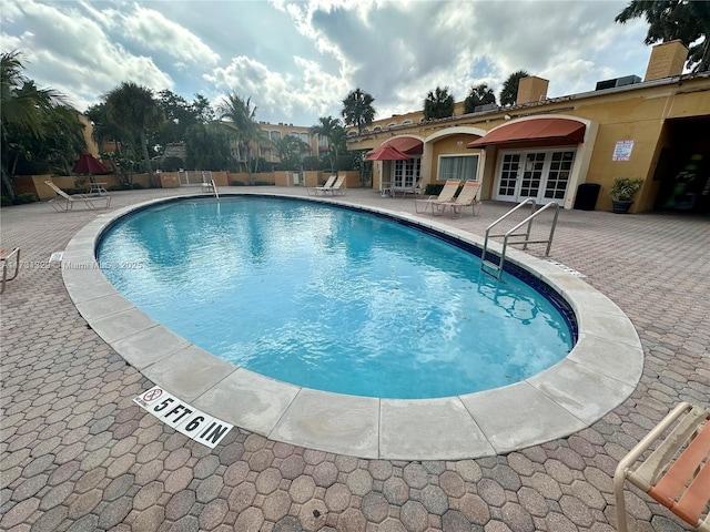 view of swimming pool with french doors and a patio area