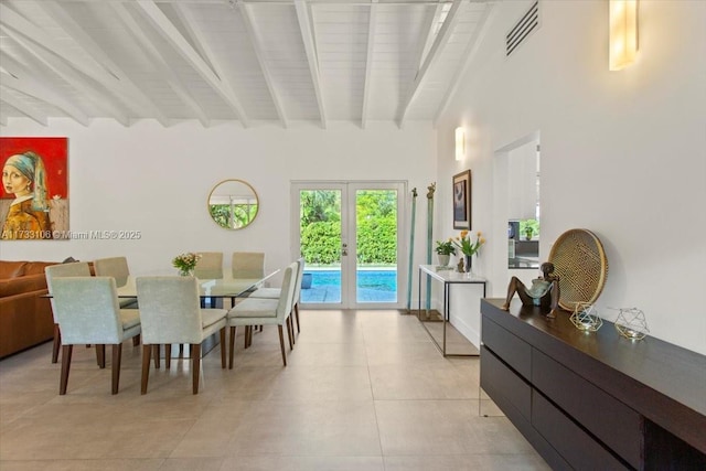 dining room featuring beam ceiling, light tile patterned flooring, french doors, and a high ceiling