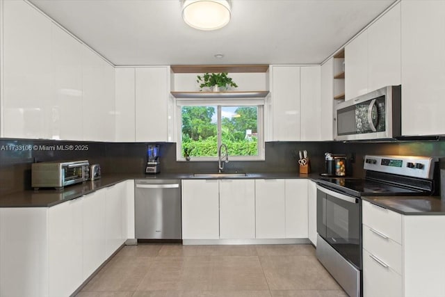 kitchen featuring white cabinetry, sink, light tile patterned flooring, and appliances with stainless steel finishes