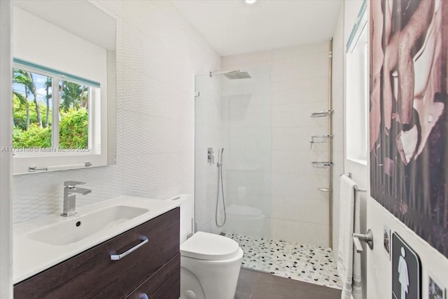 bathroom featuring tasteful backsplash, vanity, toilet, and a tile shower