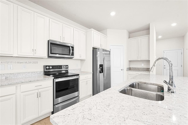 kitchen featuring sink, stainless steel appliances, white cabinets, and light stone countertops