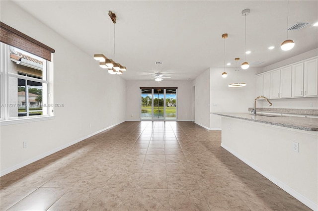 interior space with ceiling fan, sink, and light tile patterned floors