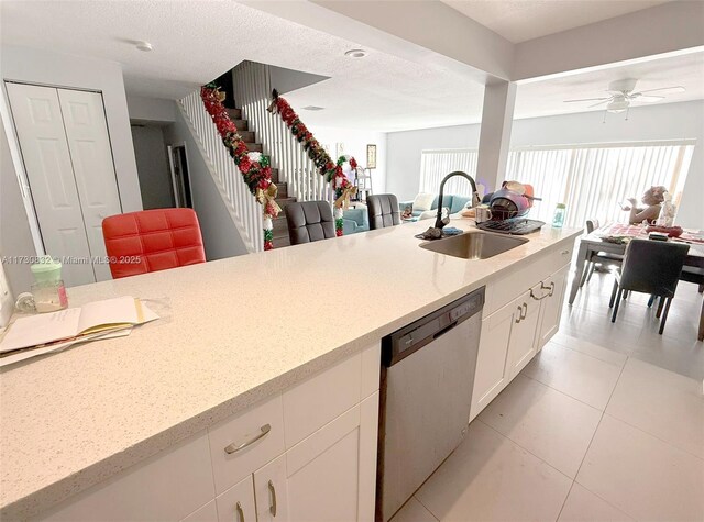 kitchen with sink, light tile patterned flooring, a textured ceiling, white cabinets, and stainless steel dishwasher