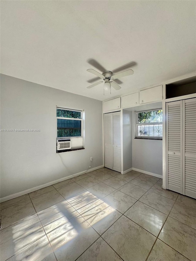 unfurnished bedroom featuring cooling unit, multiple closets, and ceiling fan