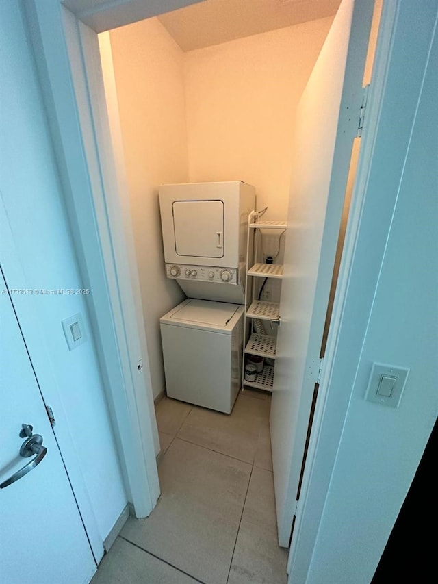 laundry area featuring light tile patterned flooring and stacked washer / drying machine