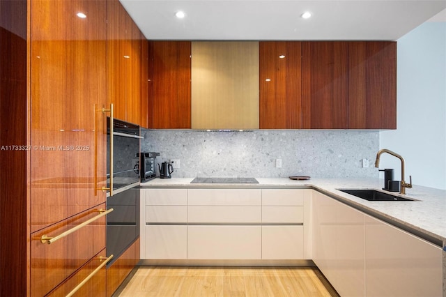 kitchen featuring tasteful backsplash, black electric stovetop, sink, and white cabinets