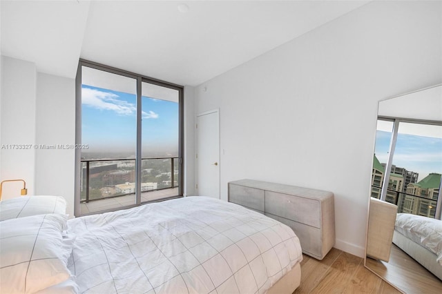 bedroom featuring multiple windows, access to outside, a wall of windows, and light wood-type flooring