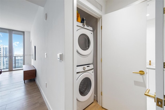 washroom with light hardwood / wood-style floors, french doors, and stacked washer / dryer