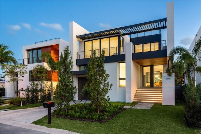 back of property featuring a balcony and a lawn