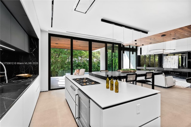 kitchen with decorative light fixtures, stainless steel gas stovetop, tasteful backsplash, expansive windows, and a healthy amount of sunlight