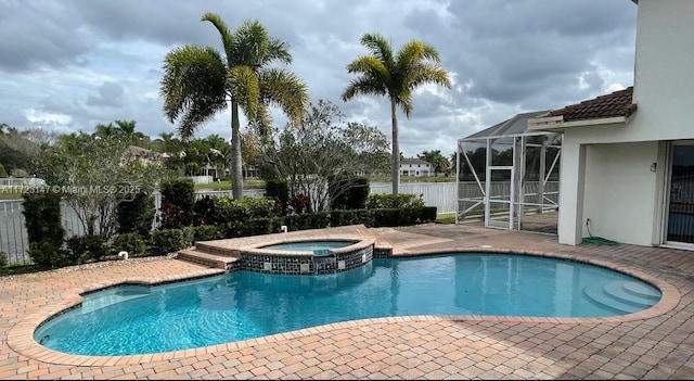 view of pool with an in ground hot tub, glass enclosure, and a patio