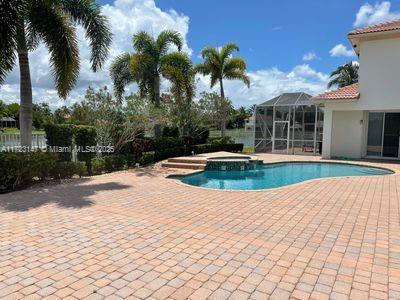 view of swimming pool with a patio area, glass enclosure, and an in ground hot tub