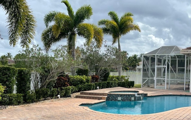 view of swimming pool featuring an in ground hot tub, glass enclosure, and a patio area