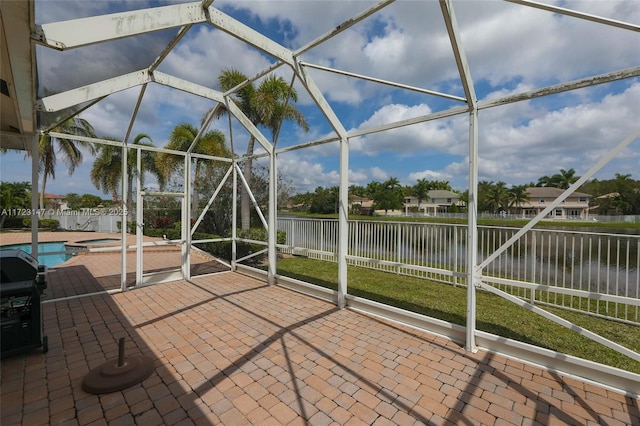 view of patio / terrace featuring a water view, glass enclosure, and a pool with hot tub