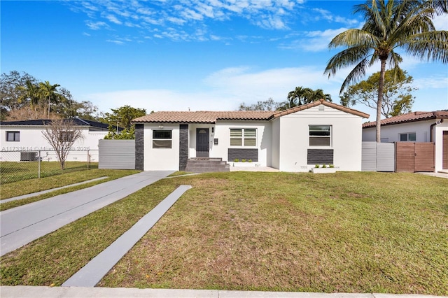 view of front of house featuring stucco siding, a tile roof, a gate, fence, and a front yard