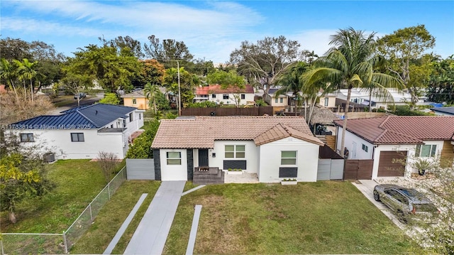 view of front of home featuring a residential view, a tiled roof, a front yard, and fence private yard