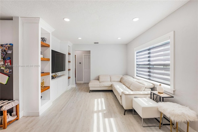 living area featuring recessed lighting, visible vents, light wood-style flooring, and a textured ceiling