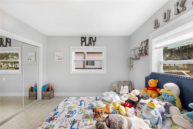 bedroom with multiple windows, wood finished floors, and baseboards