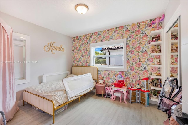 bedroom with wood finished floors and wallpapered walls