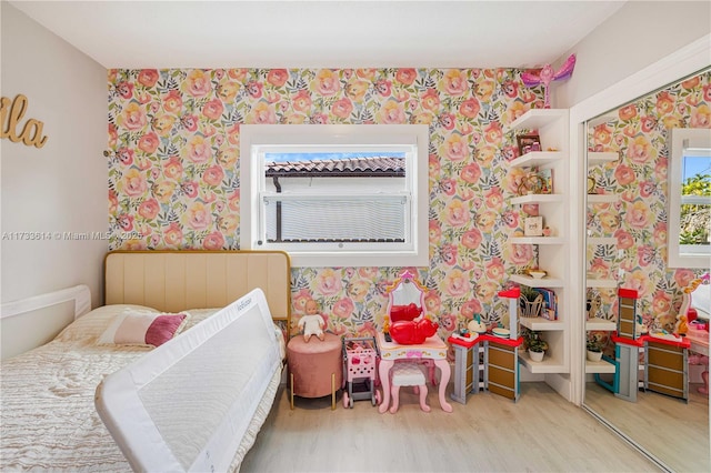 bedroom with wallpapered walls and wood finished floors