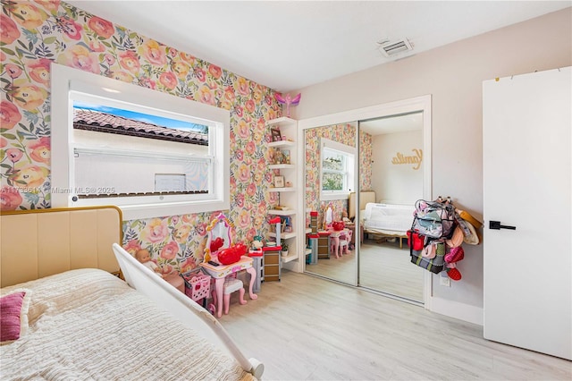 bedroom featuring wallpapered walls, visible vents, a closet, and wood finished floors