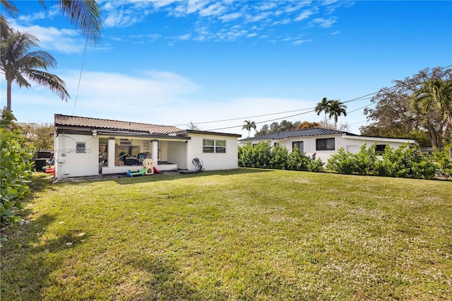 rear view of property with a yard and stucco siding