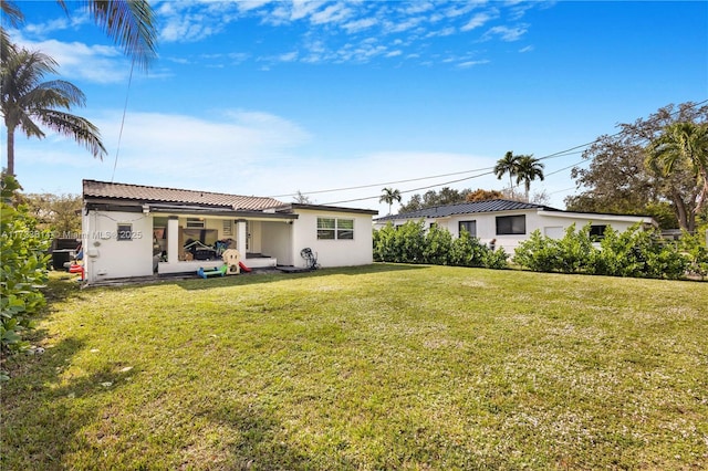 rear view of property with a lawn and stucco siding