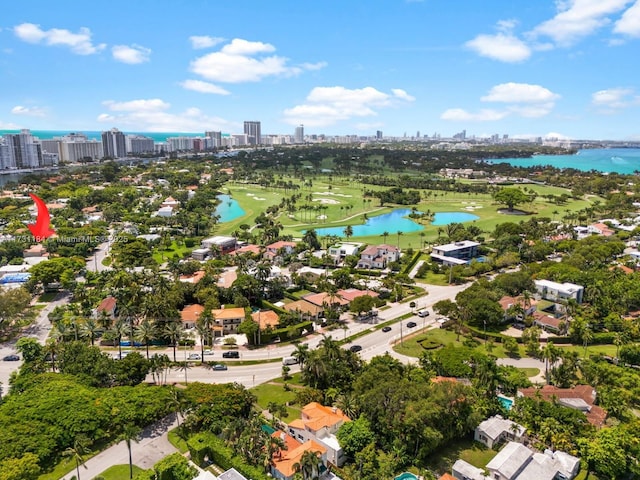 drone / aerial view featuring golf course view, a water view, and a city view