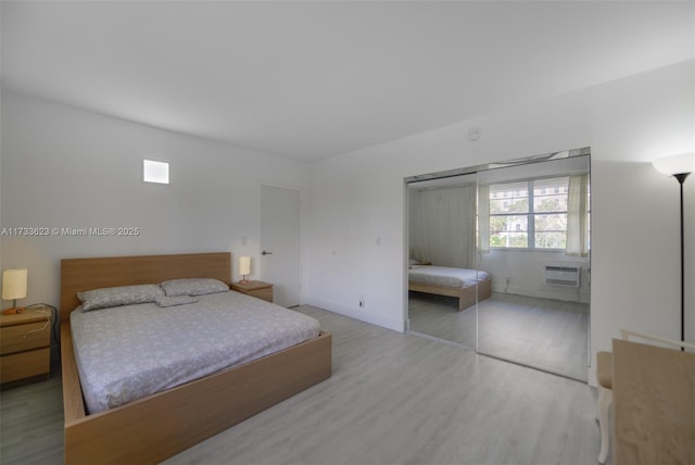 bedroom with an AC wall unit, a closet, and hardwood / wood-style flooring