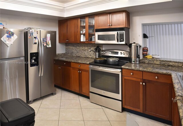 kitchen featuring light tile patterned floors, backsplash, dark stone counters, and appliances with stainless steel finishes