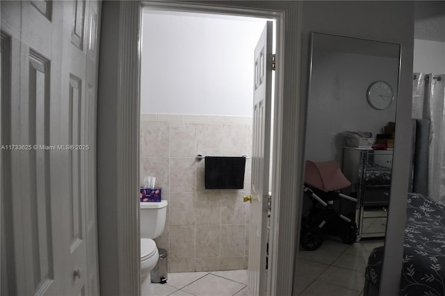 bathroom featuring tile patterned floors, toilet, and tile walls