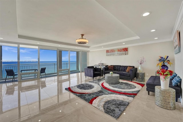 living room featuring a tray ceiling, a water view, recessed lighting, and crown molding