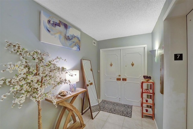 entryway featuring a textured ceiling, light tile patterned floors, and visible vents