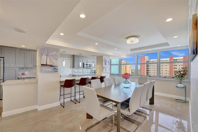 dining area featuring baseboards, a raised ceiling, a city view, and recessed lighting