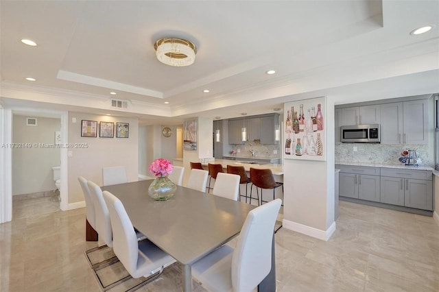 dining room featuring a tray ceiling, visible vents, baseboards, and recessed lighting