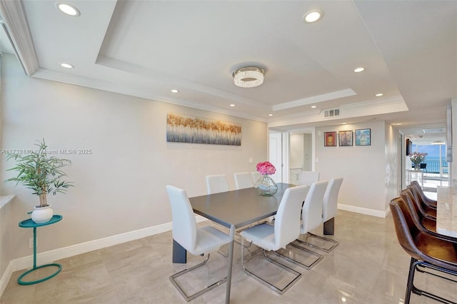 dining space with ornamental molding, a raised ceiling, visible vents, and baseboards