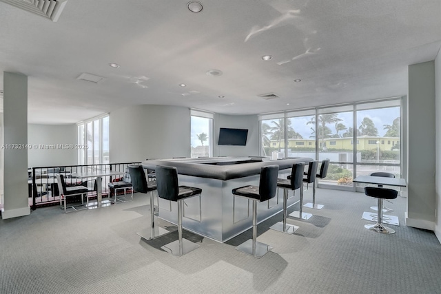 kitchen featuring a breakfast bar, light carpet, visible vents, and expansive windows