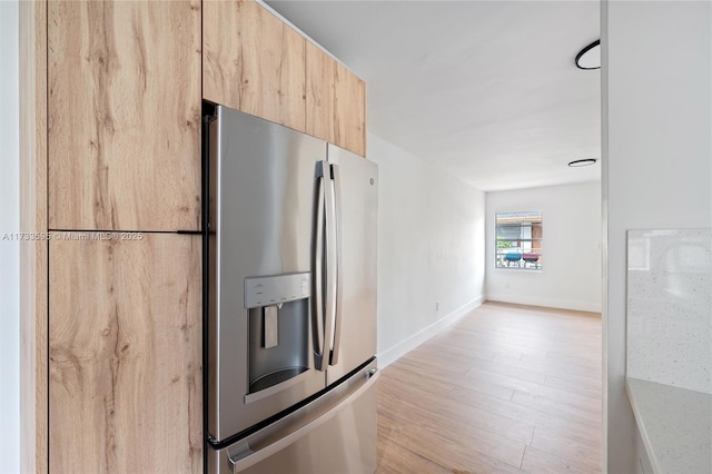 kitchen with light brown cabinetry, stainless steel fridge with ice dispenser, and light hardwood / wood-style floors