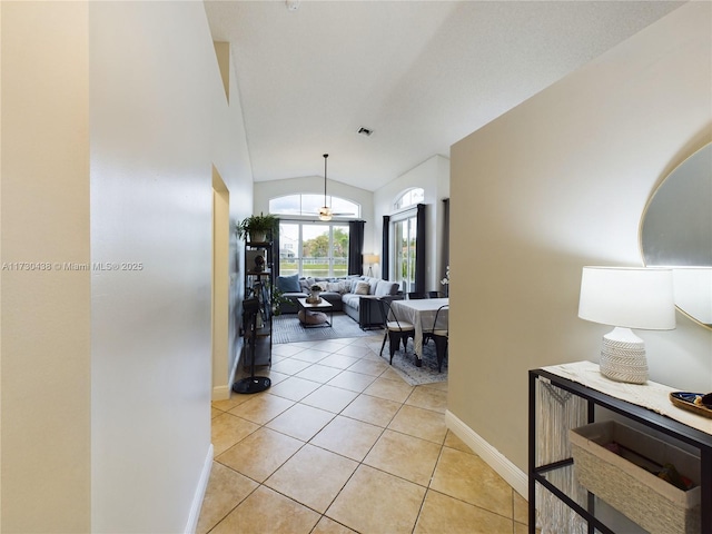 hallway with lofted ceiling and light tile patterned floors