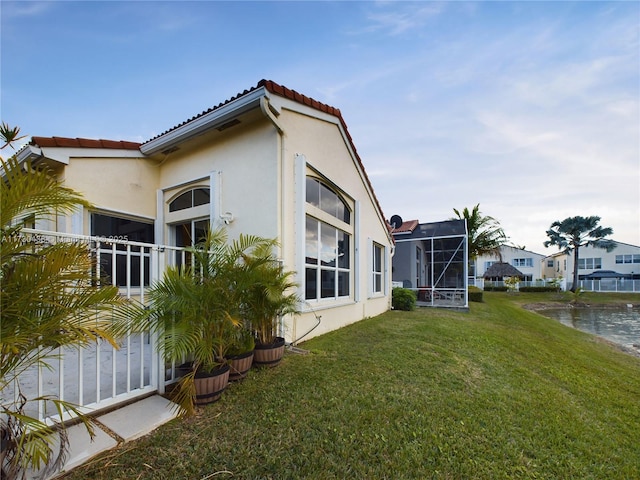 view of side of property with a lanai and a lawn