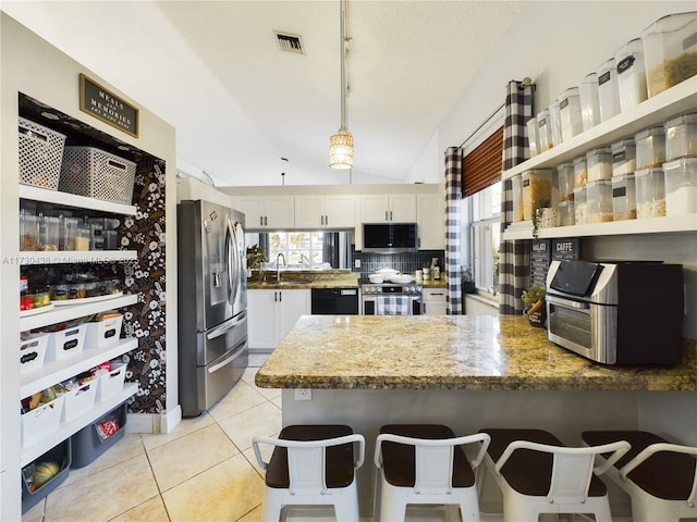 kitchen featuring a breakfast bar area, appliances with stainless steel finishes, white cabinetry, decorative light fixtures, and kitchen peninsula