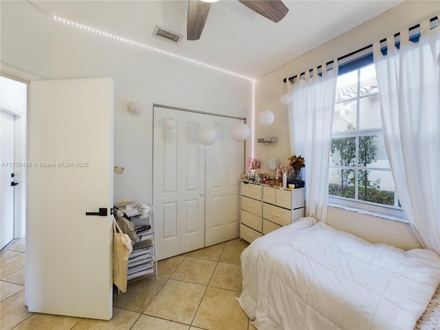 tiled bedroom featuring ceiling fan, a closet, and multiple windows