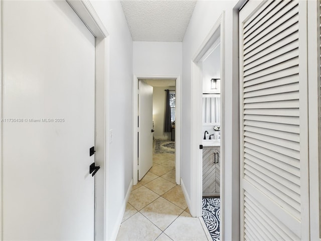 corridor featuring light tile patterned floors and a textured ceiling