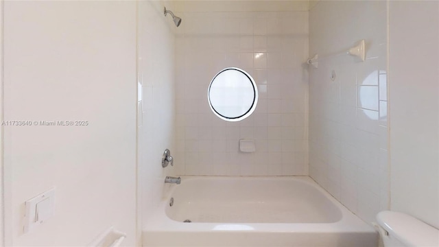 bathroom with toilet and tiled shower / bath