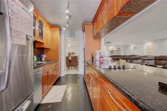 kitchen featuring decorative backsplash, dark stone counters, dark tile patterned floors, and appliances with stainless steel finishes