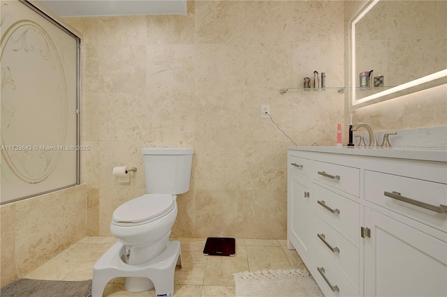 bathroom featuring vanity, tile walls, tile patterned floors, and toilet