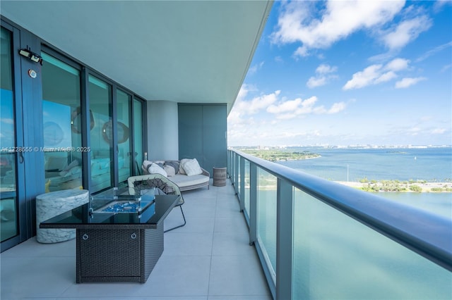 balcony featuring a water view and an outdoor fire pit